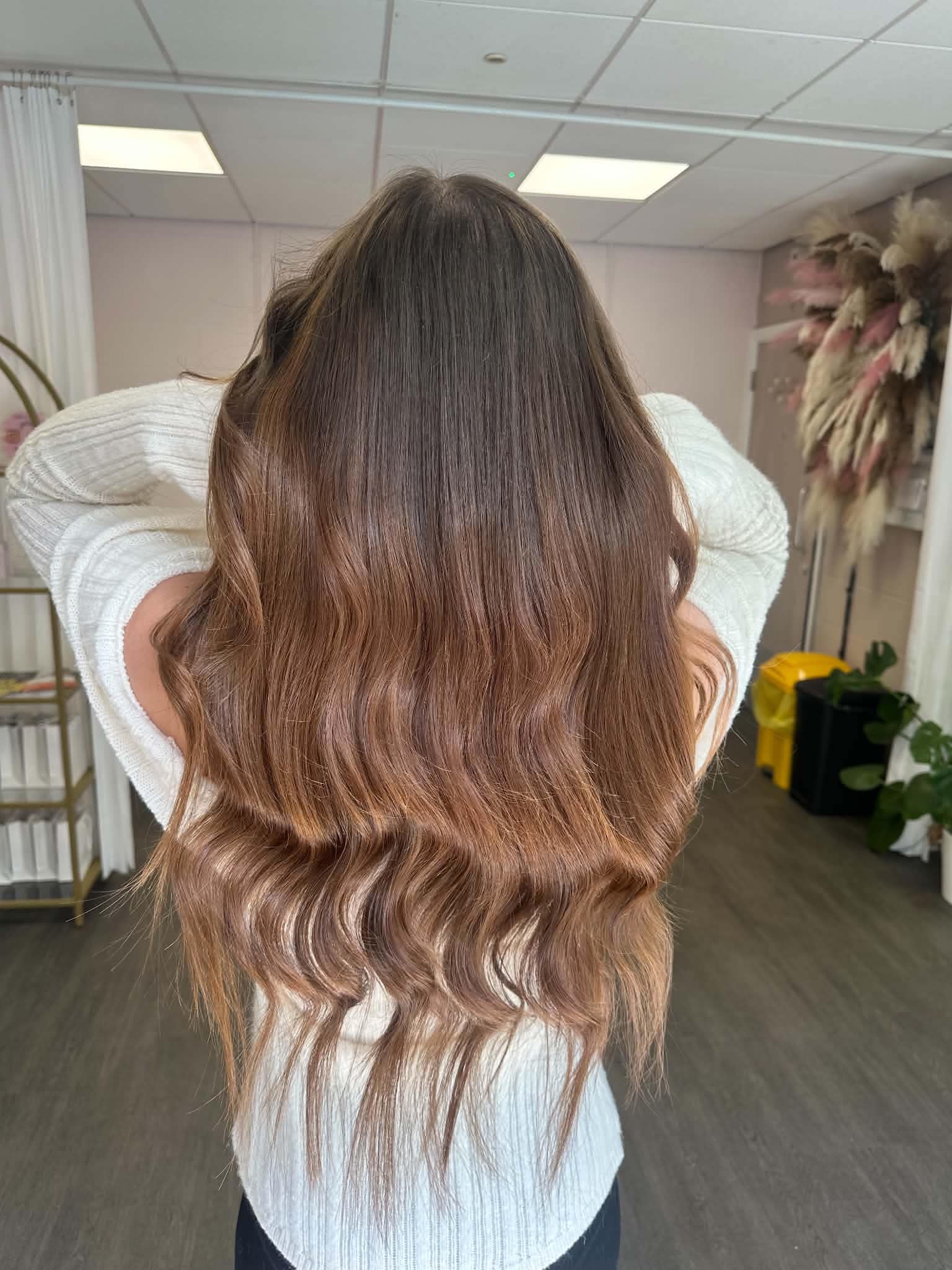 Glossy brunette hair extensions styled in soft waves.
